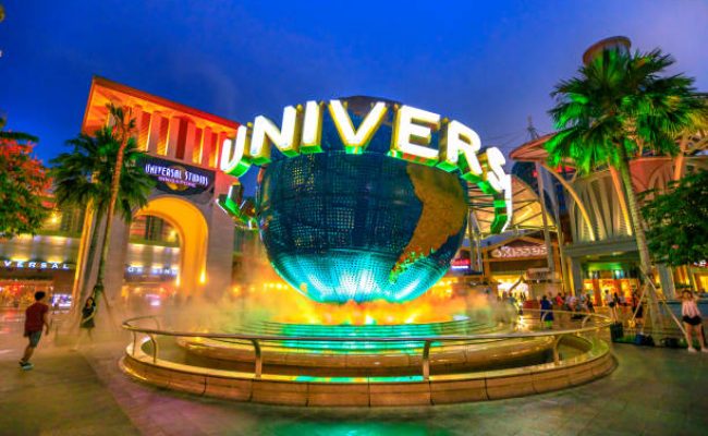 Singapore - May 2, 2018: Universal Studios world globe in green light, with tourists visiting this Hollywood movie theme park in Sentosa island.